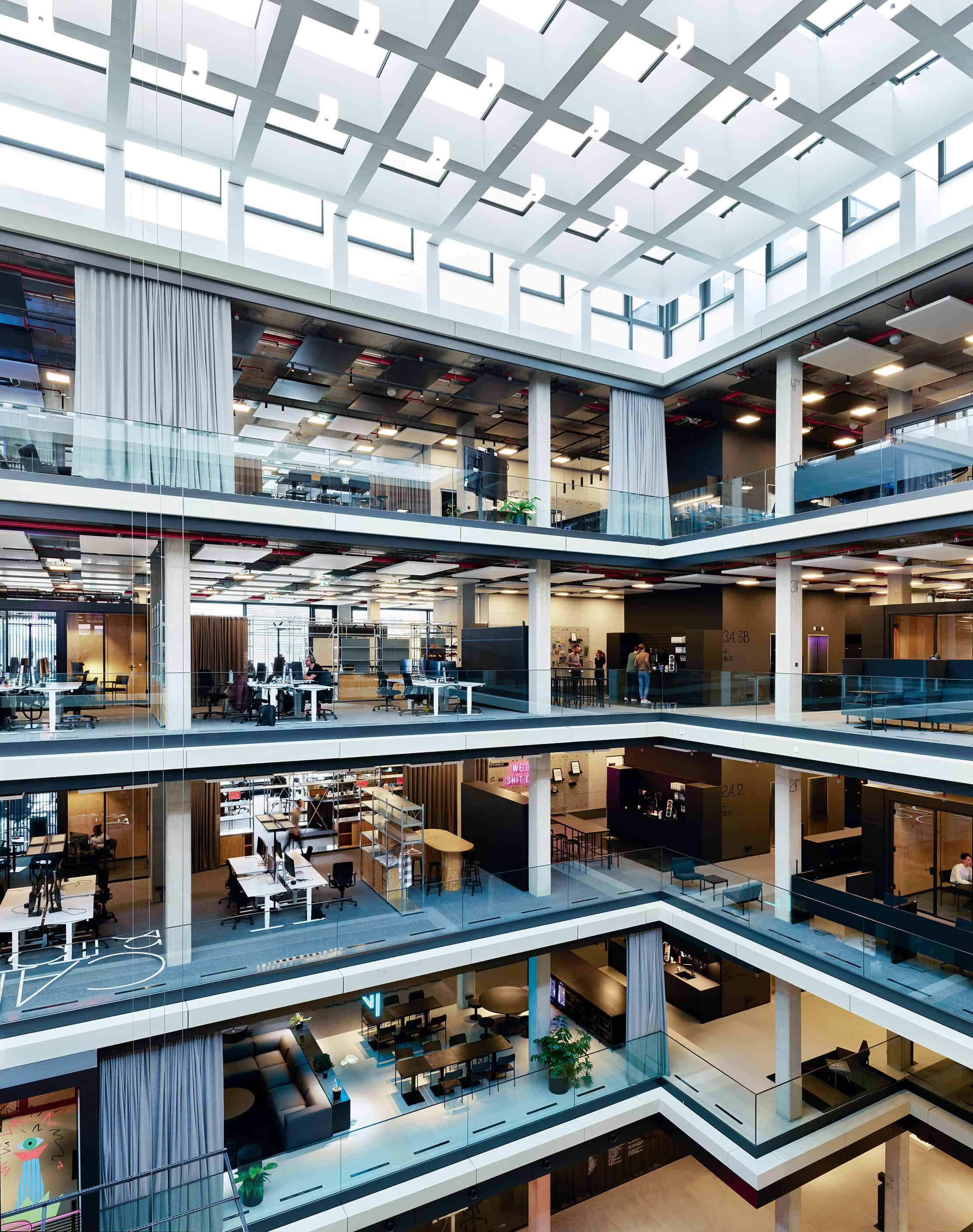 serviceplan's new munich headquarters - the view of a modern office atrium, with floors of bustling office space and break out areas.