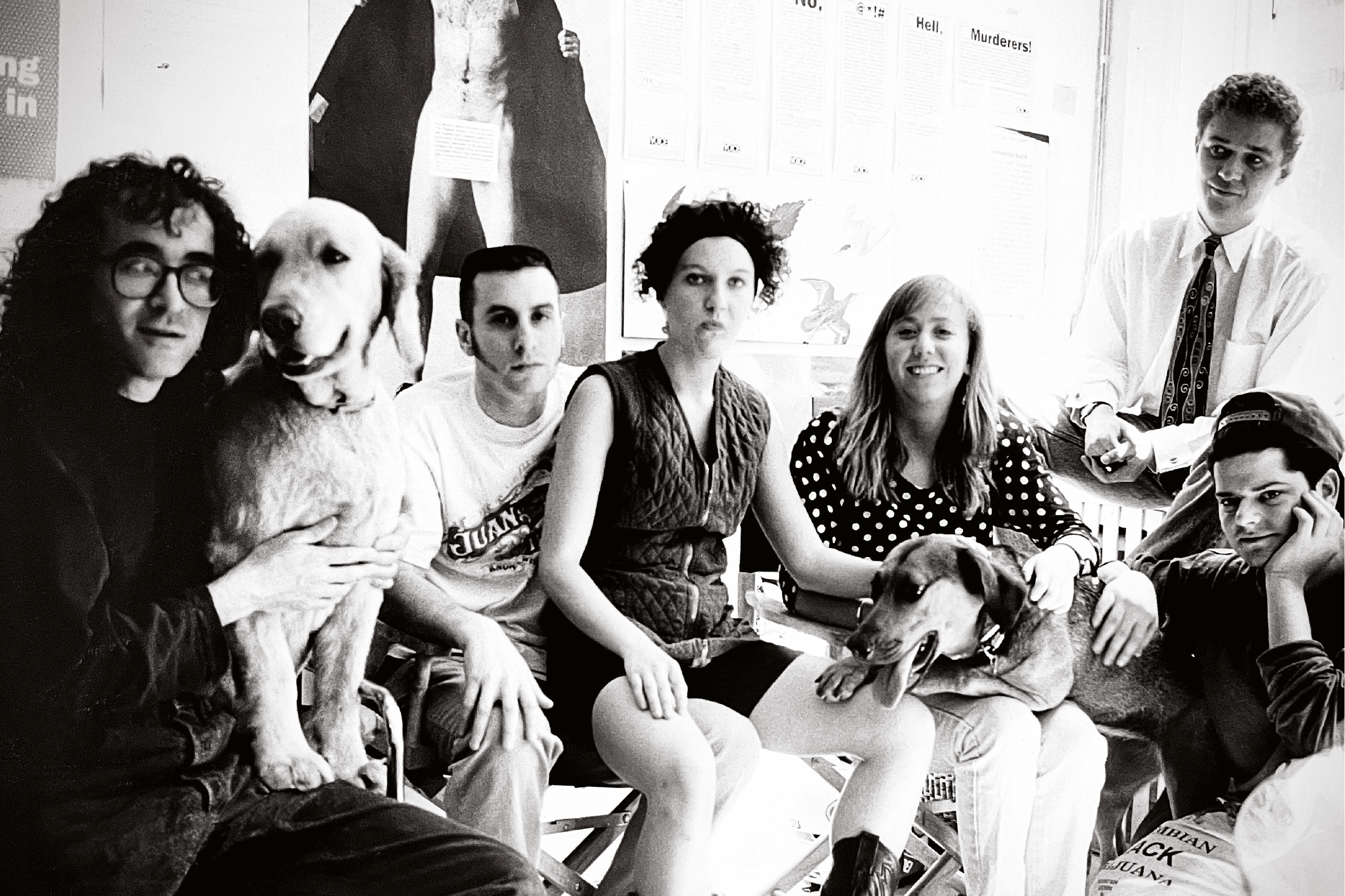 Black and white photo of the Early Mad Dogs Crew. Six young men and women plus two dogs sit around looking fashionable and cool.